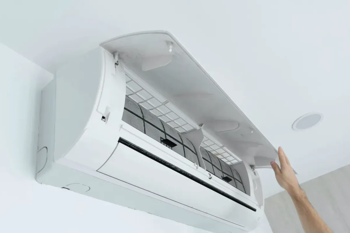 Hand opening the cover of a wall-mounted ductless air conditioner